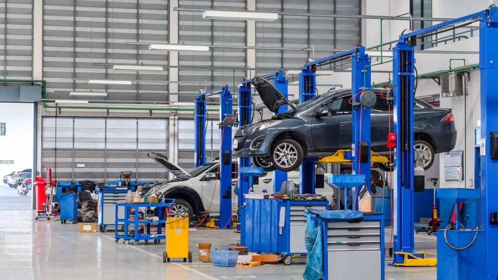 Several vehicles raised on hydraulic lifts in an automotive workshop.