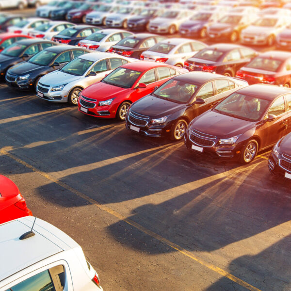 Rows of new cars parked outside a dealership on a sunny day.