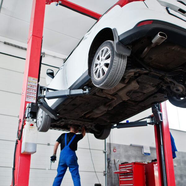 Car lifted on a red hydraulic ramp in a garage.