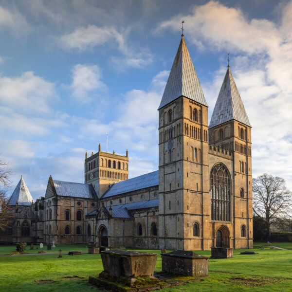 Exterior of a historic church surrounded by trees and gravestones.