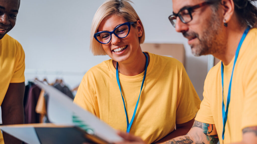 Smiling volunteers in yellow shirts reviewing documents together.