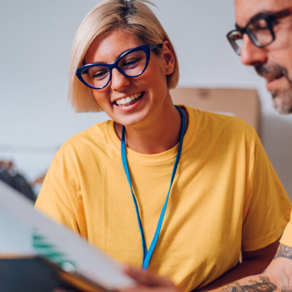 Smiling volunteers in yellow shirts reviewing documents together.