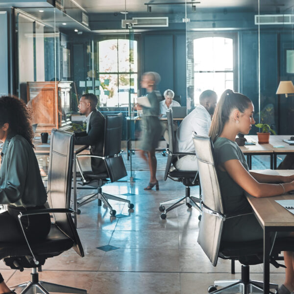 Team working in a bright open-plan office with large windows.