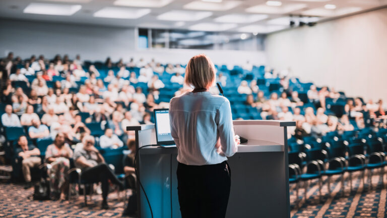 Speaker giving a presentation to an audience in a university lecture hall.
