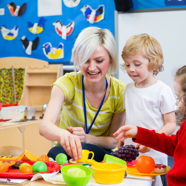Primary school teacher helping children with a classroom activity.