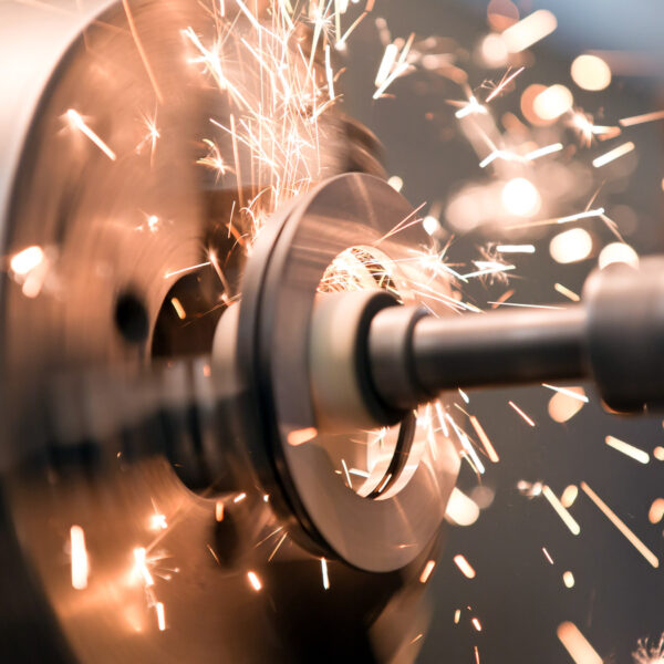 Close-up of CNC machine cutting metal with bright sparks.