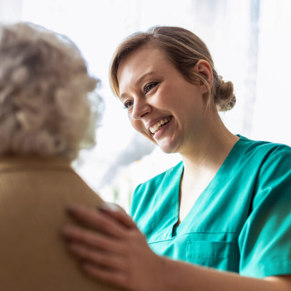 Smiling healthcare worker talking to an elderly patient.