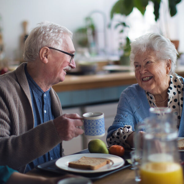 Elderly people enjoying breakfast and conversation together.