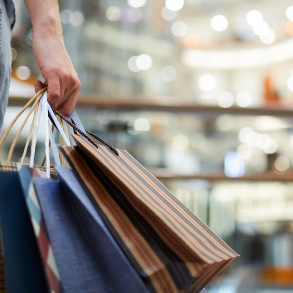 Person holding several colourful shopping bags in a retail centre.