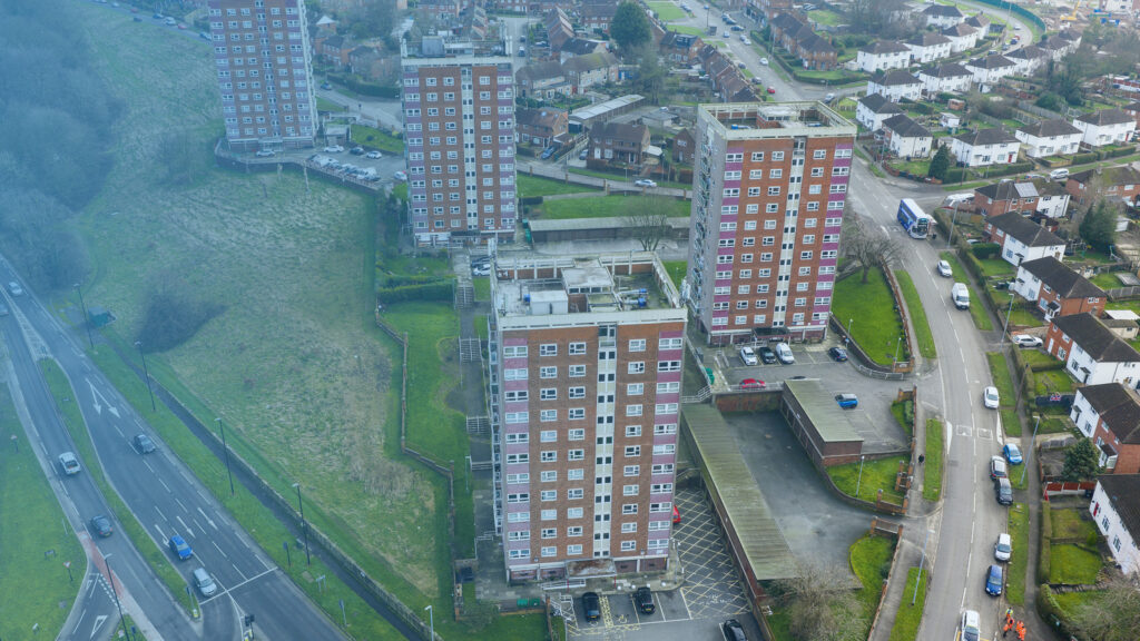 Aerial view of residential high-rise tower blocks and surrounding housing estate with roads and green space.